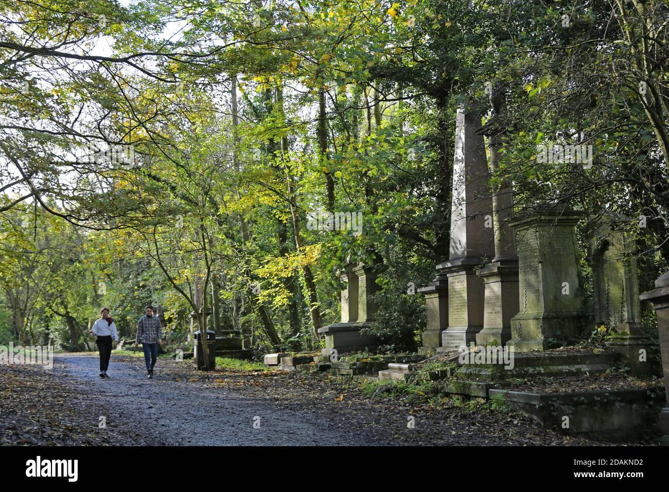 A couple walk in Nunhead Cemetery, south London, UK. An impressive Victorian cemetery now wild and overgrown, but popular with local people. Stock Photo