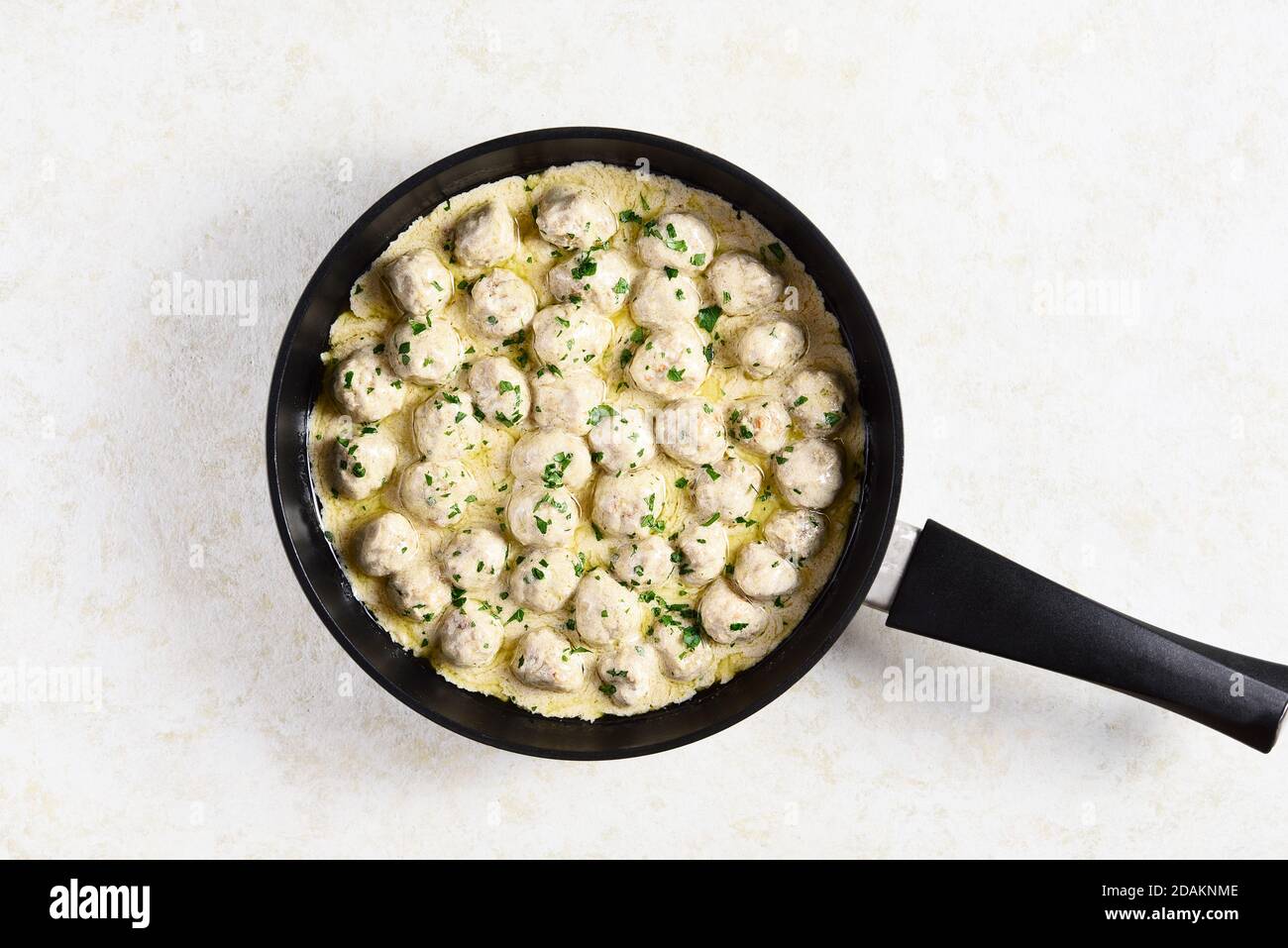 Close up of swedish meatballs with creamy white sauce in frying pan over light stone background with copy space. Top view, flat lay Stock Photo
