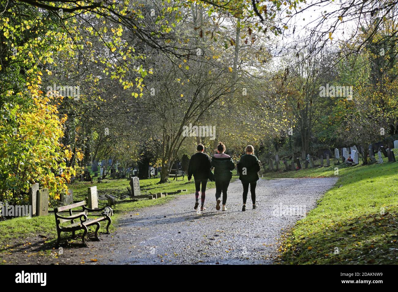 Three girls walk in Nunhead Cemetery, south London, UK. An impressive Victorian cemetery now wild and overgrown, but popular with local people. Stock Photo