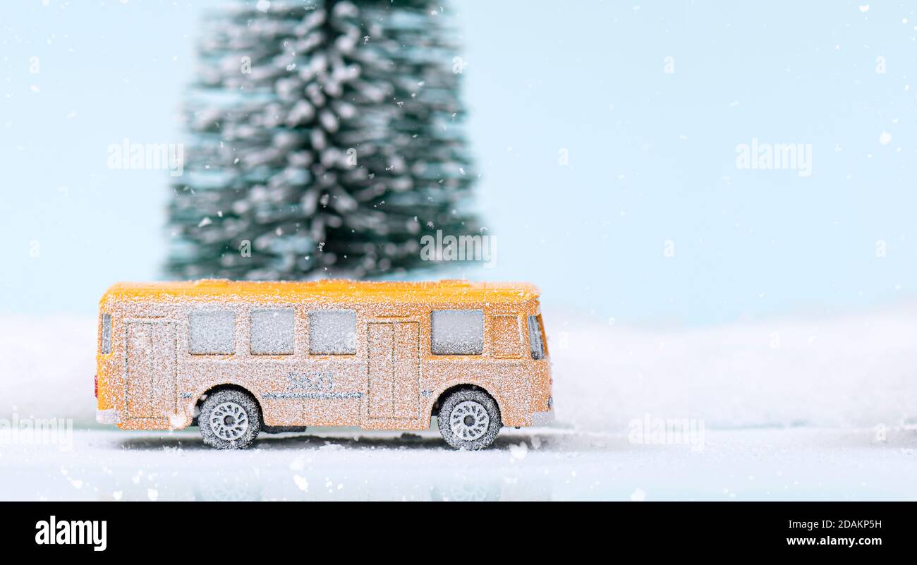 Christmas or New Year composition, decoration with glass ball snow globe, yellow bus and fir tree covered by snow on glitter background Stock Photo