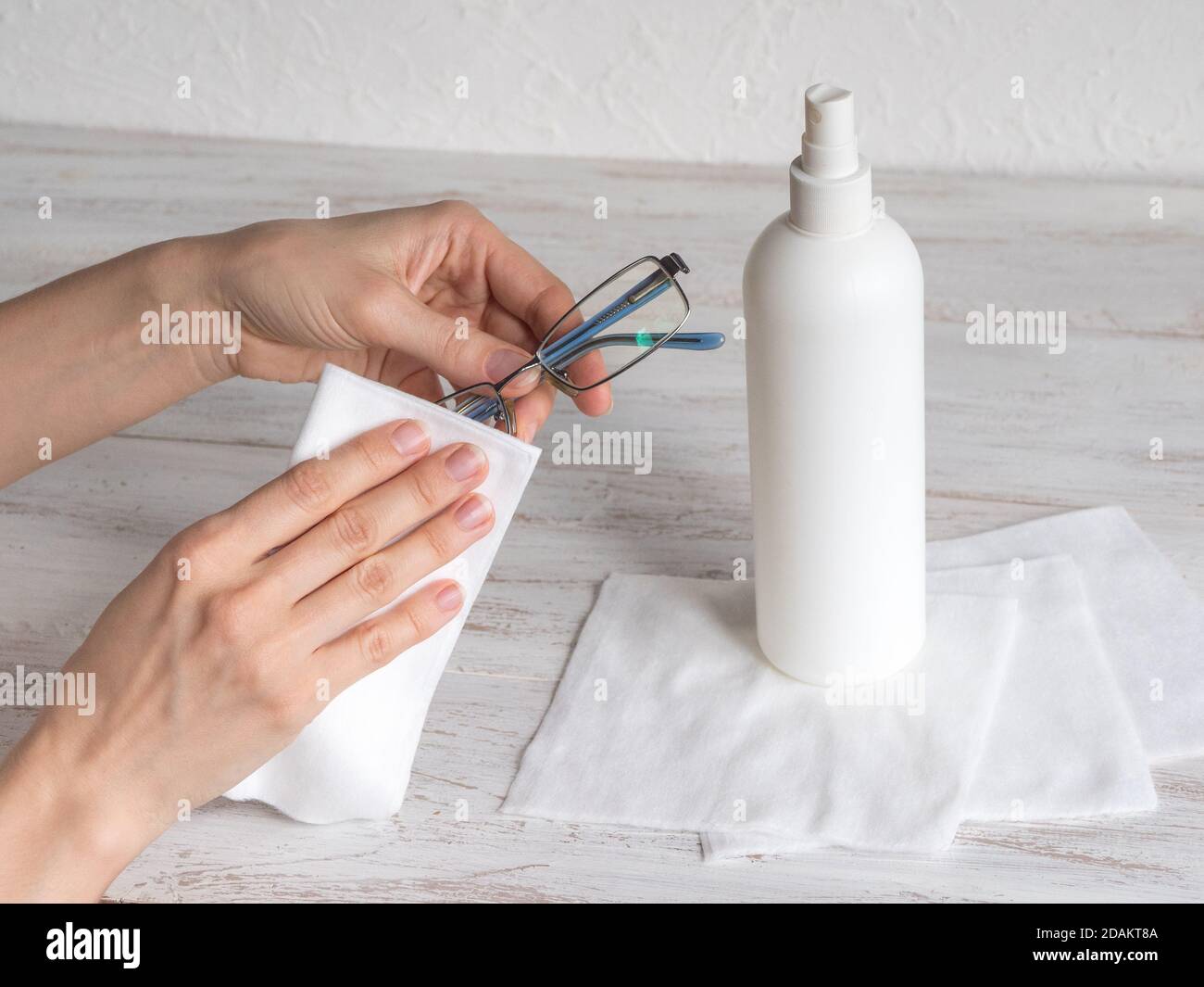Woman hand wiping glasses with disinfectant wipes due to corona virus pandemic. Stock Photo
