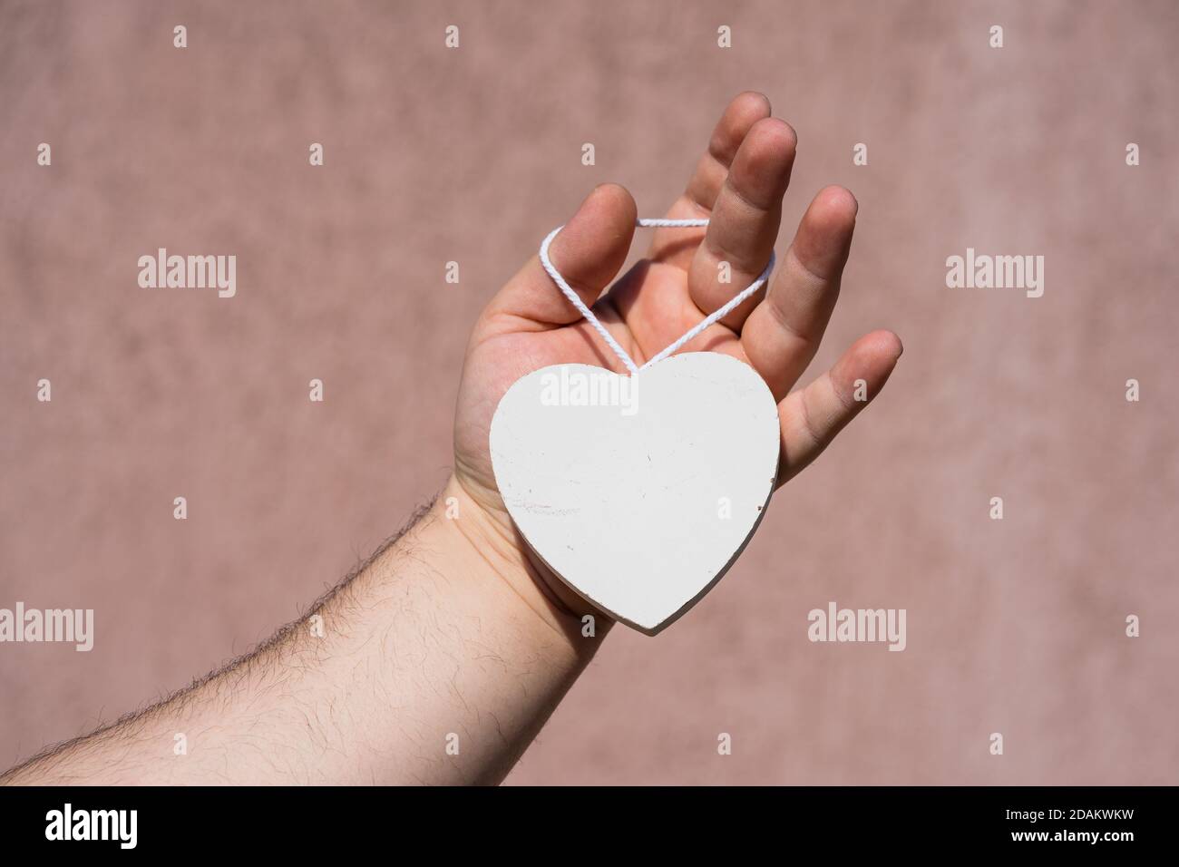 Hands holding a white wooden heart shaped object decoration isolated ...