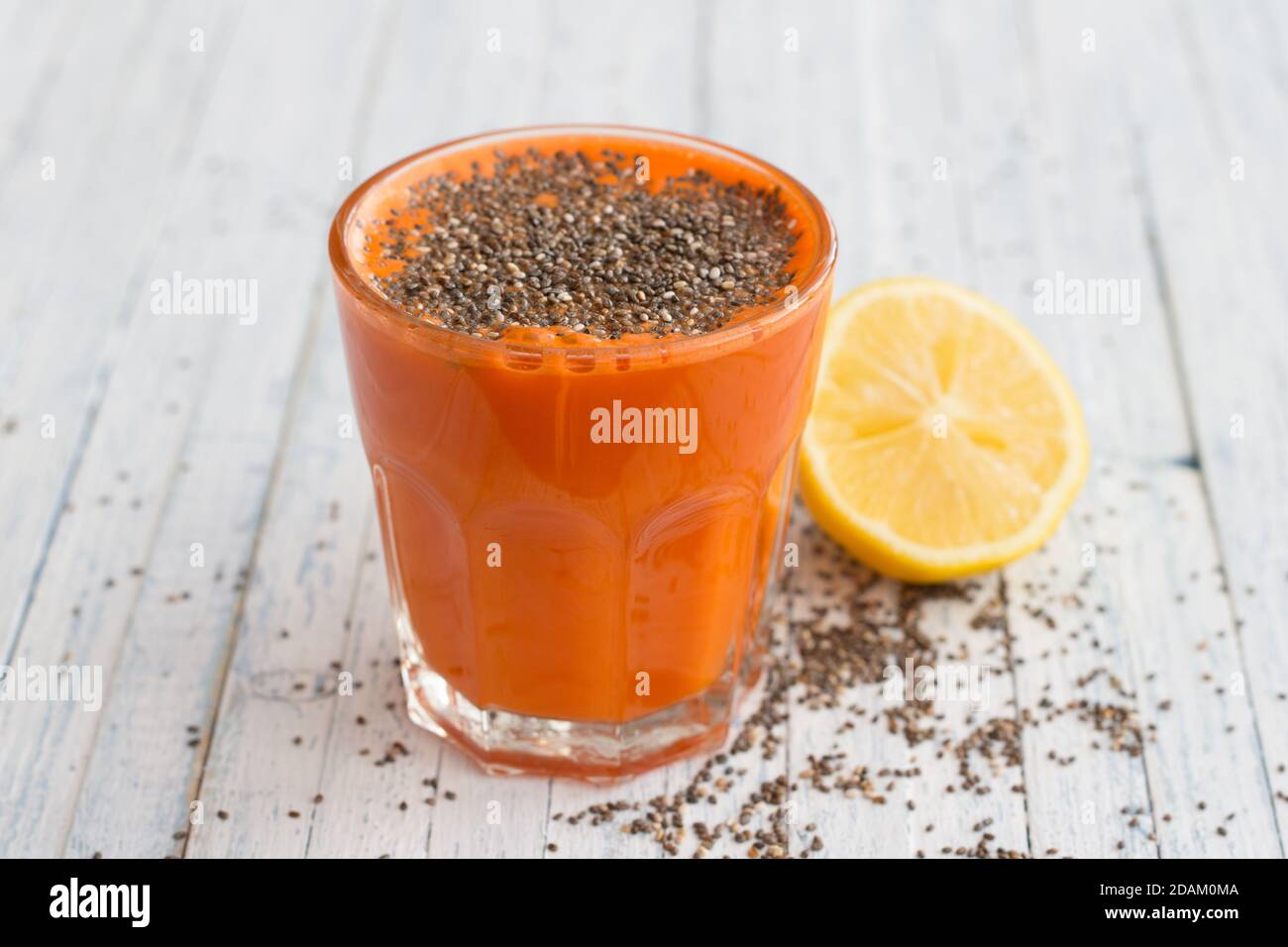 Carrot cocktail with lemon and chia seeds in a glass on a light blue background, selective focus. Healthy delicious drink Stock Photo