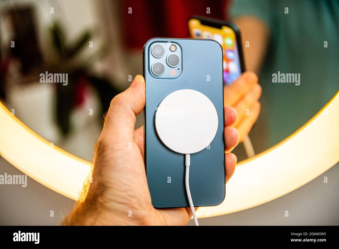 Paris France Nov 11 Man Hand Holding In Front Of Mirror New Iphone 12 Pro Max 5g Smartphone Model By Apple Computers Close Up Of Pacific Blue Mobile Phone Device Charging