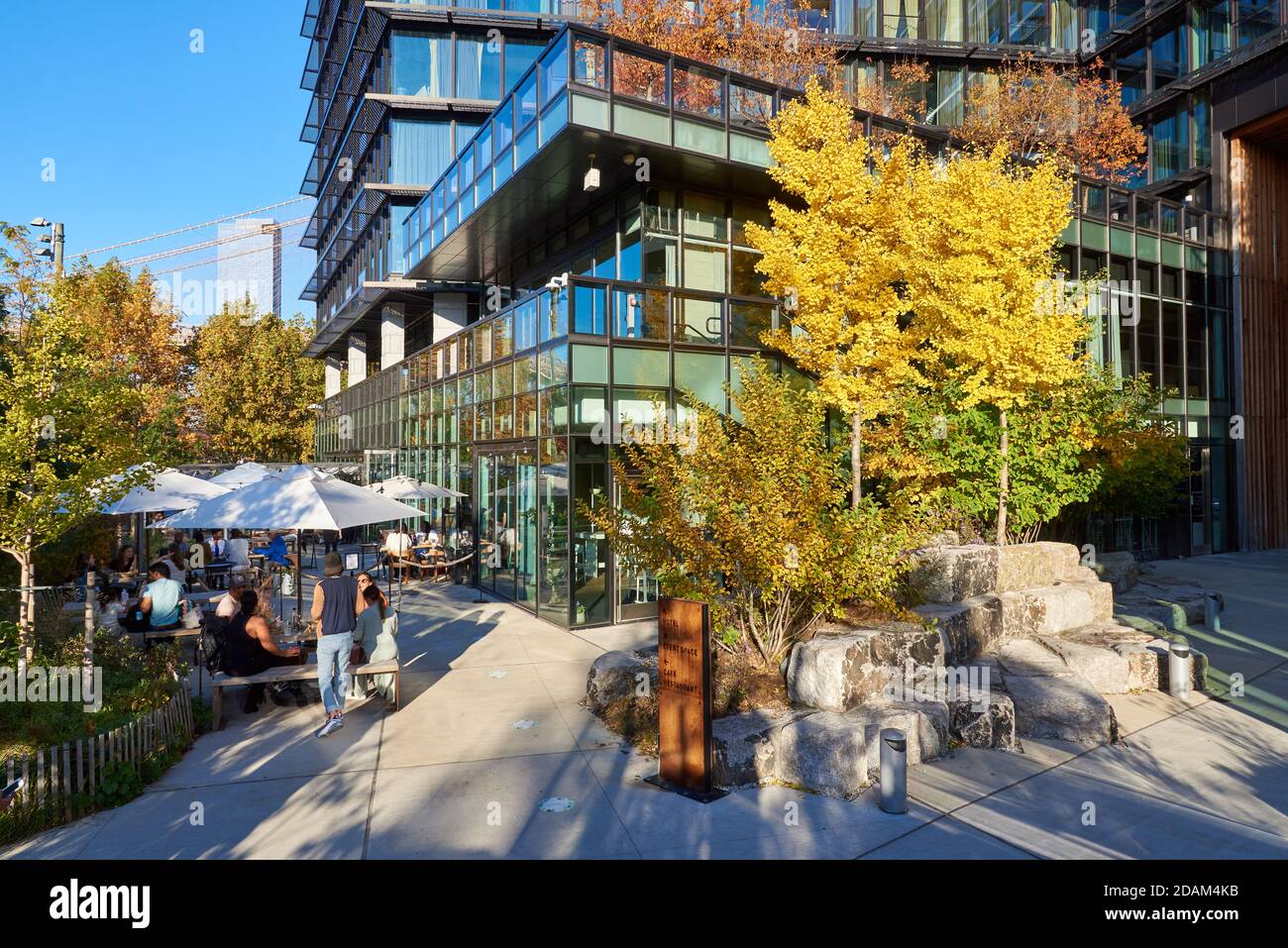 Groups of people sit at tables outside at the Osprey Restaurant in Brooklyn Bridge Park on a sunny autumn day. Stock Photo
