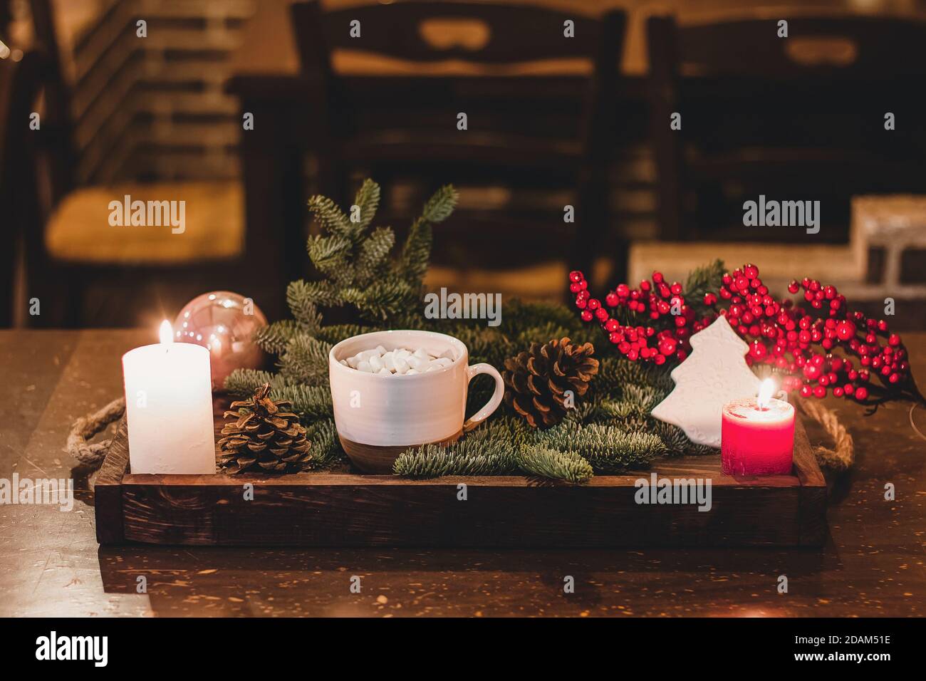 Christmas hot chocolate with mini marshmellows in an old ceramic mug with candles on a wooden background. Stock Photo