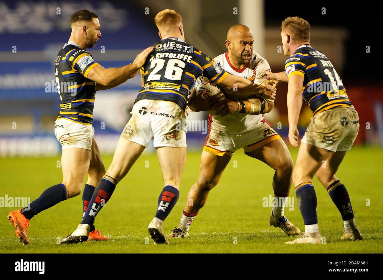 Catalans Dragons' Sam Moa (centre) is tackled by Leeds Rhinos' Alex Sutcliffe and Brad Dwyer during the Betfred Super League Play-Off match at The Halliwell Jones Stadium, Warrington. Stock Photo