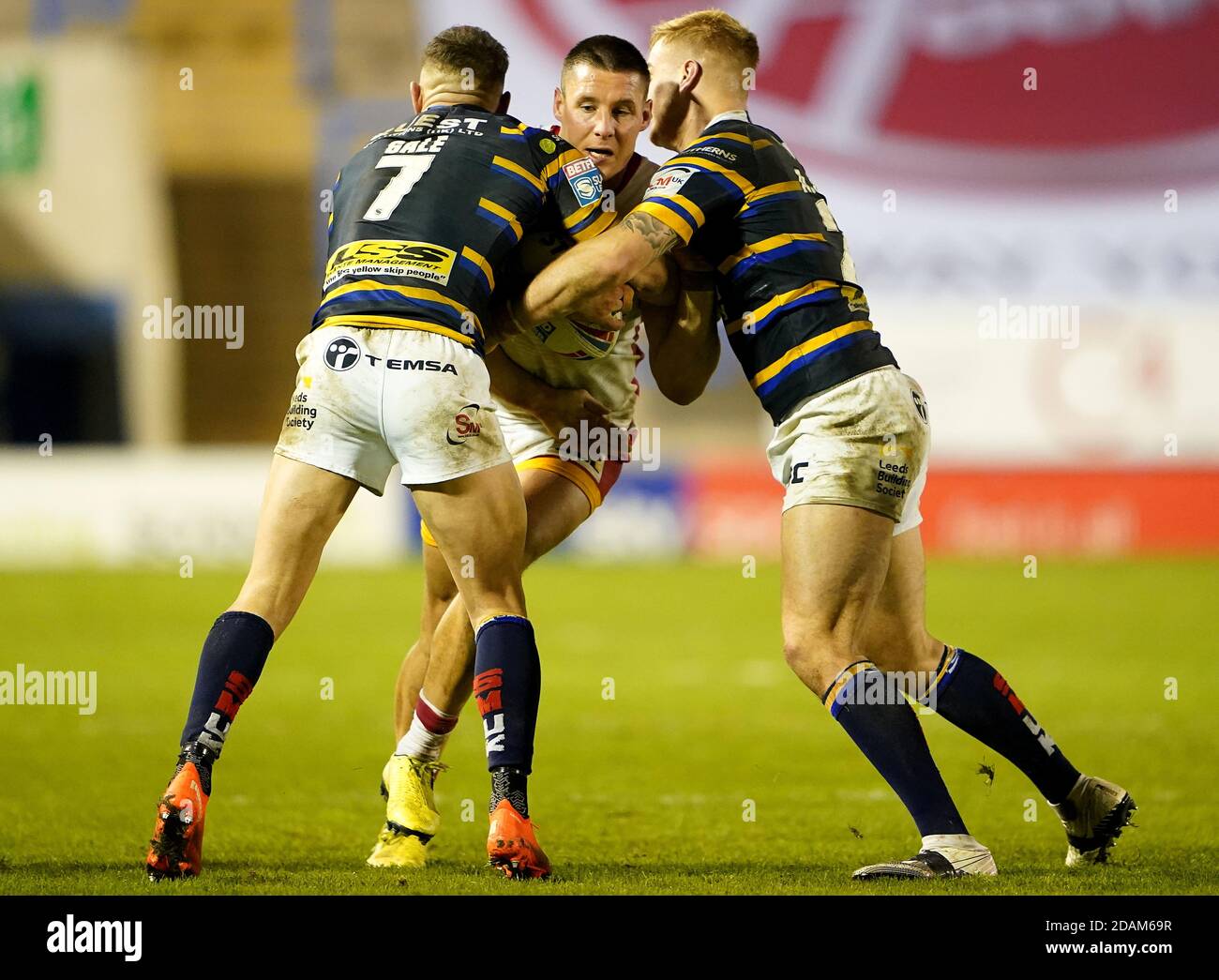 Catalans Dragons' Joel Tomkins (centre) is tackled by Leeds Rhinos' Luke Gale (left) and Alex Sutcliffe during the Betfred Super League Play-Off match at The Halliwell Jones Stadium, Warrington. Stock Photo