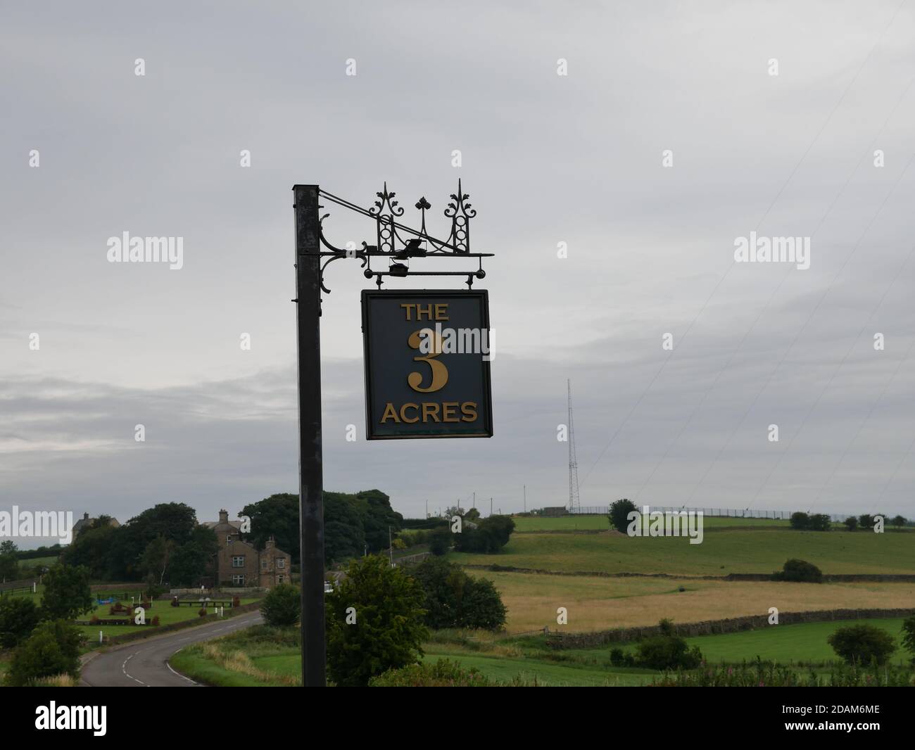 Sign hung from wooden post writing in gold letters the 3 acres fields and mast in the background Stock Photo