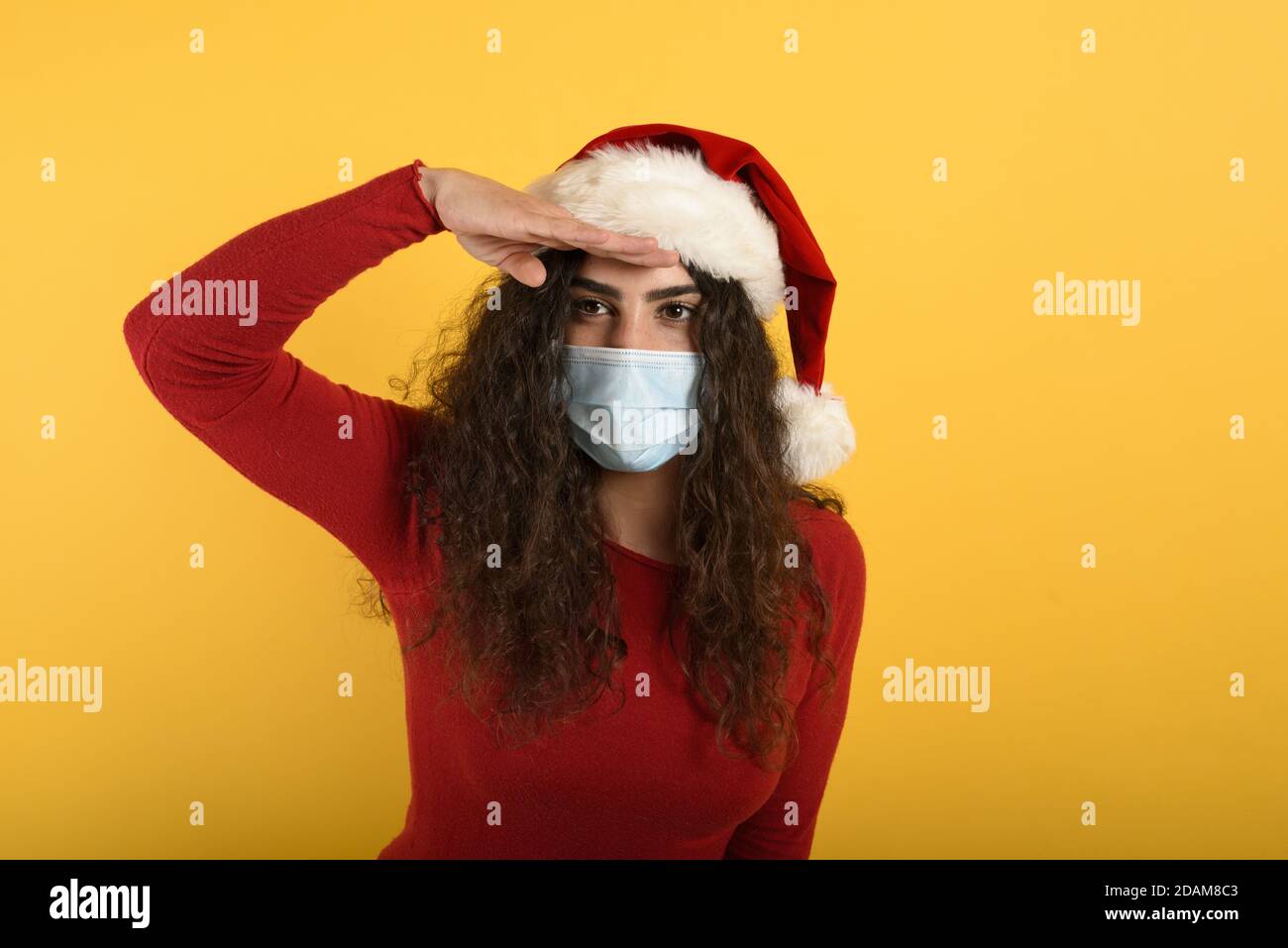 Woman with face mask look far for something. yellow background Stock Photo