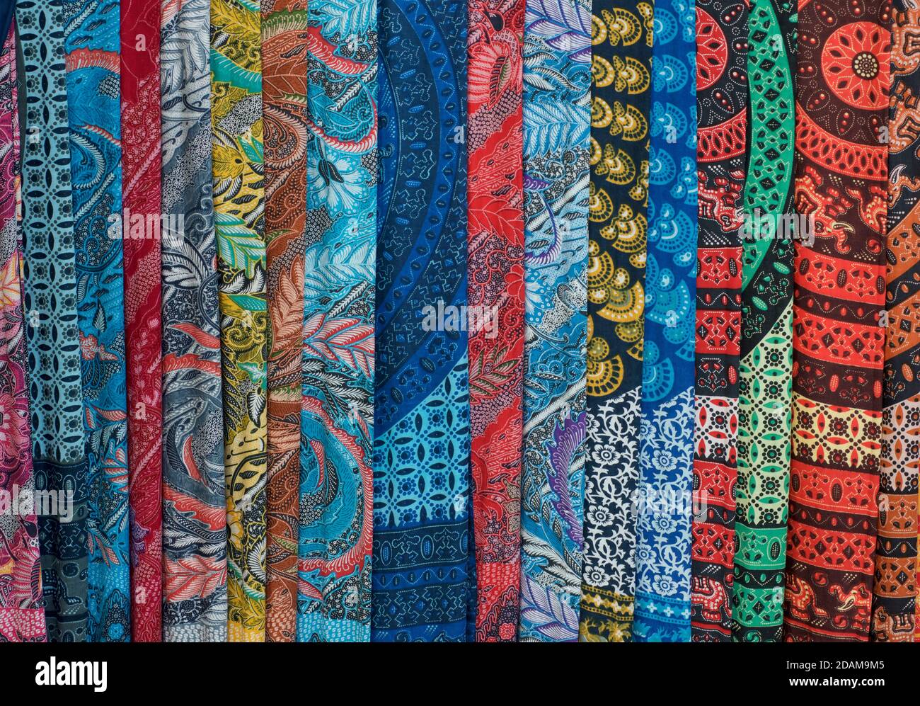 A selection of Balinese fabrics; brightly coloured sarongs for sale on a market stall. Bali. Indonesia Stock Photo