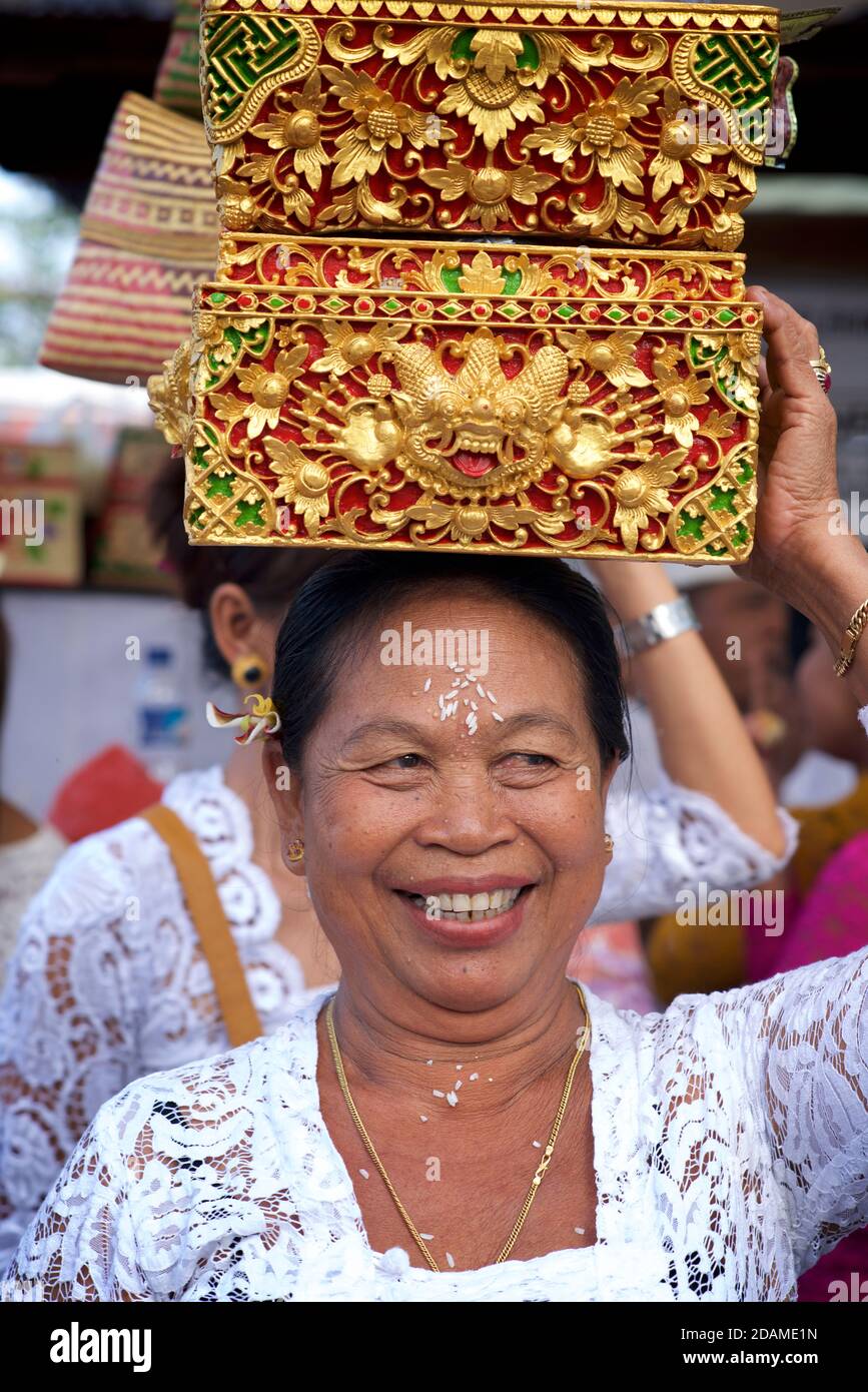 Balinese woman in ceremonial dress with offering in a traditional basket, Sakenan temple, Bali, Indonesia Stock Photo
