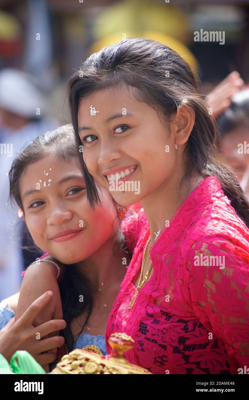 Balinese girls in festive attire arm in arm and smiling. Sakenan temple, Bali, Indonesia Stock Photo