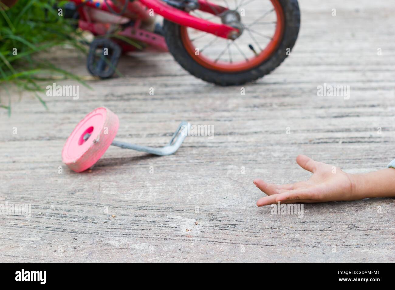 horizontal photo of closeup bicycle for children accident on the city street with hand of a child on the ground Stock Photo