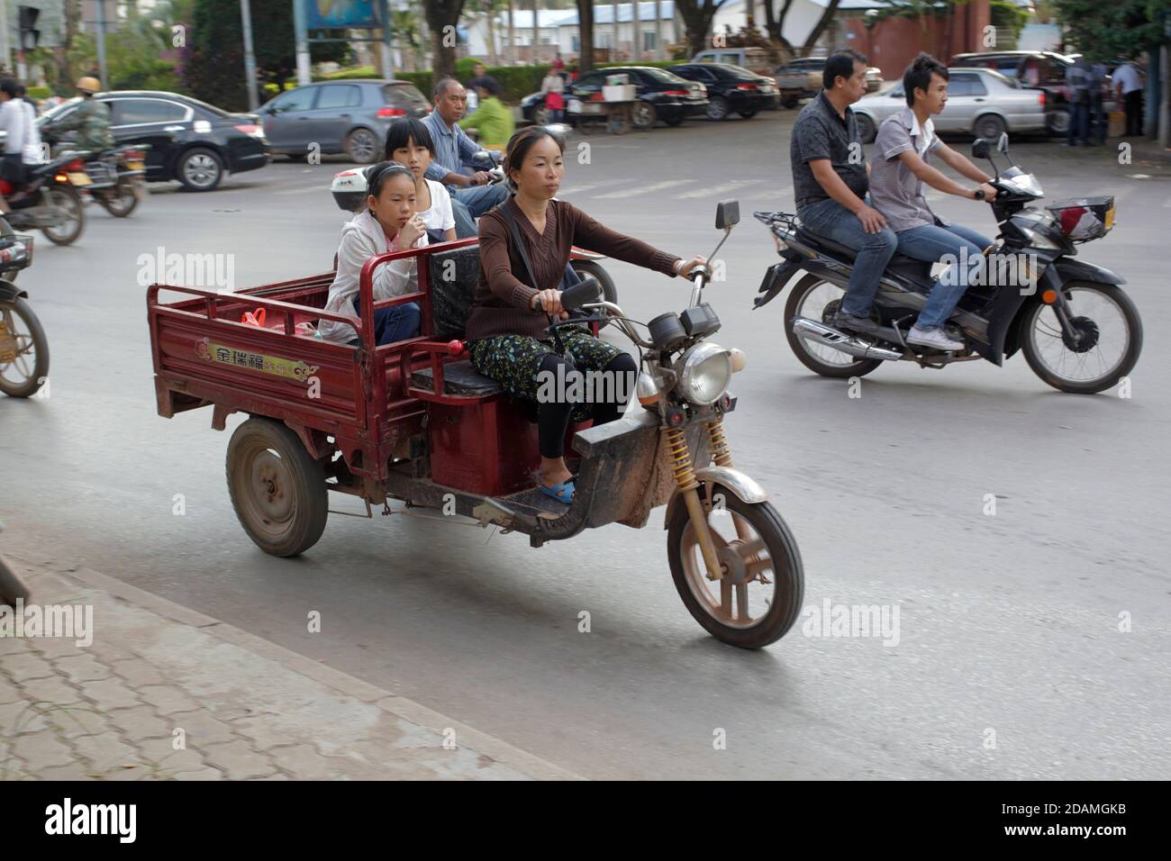 Street scene, lady with children driving tricycle, Jinghong, Yunnan
