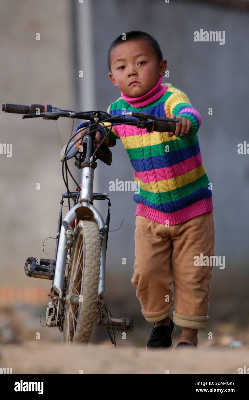 Veretical view of boy pushing bicycle, Mahuangqing, Lincang Prefecture, Yunnan Province, China Jan 2013 Stock Photo