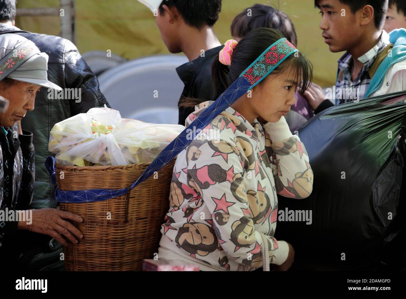 Side view of young woman carrying heavy basket of eggs, Market day at Wumulong, Yongde County, Lincang Prefecture,Yunnan, China Jan 2013 Stock Photo