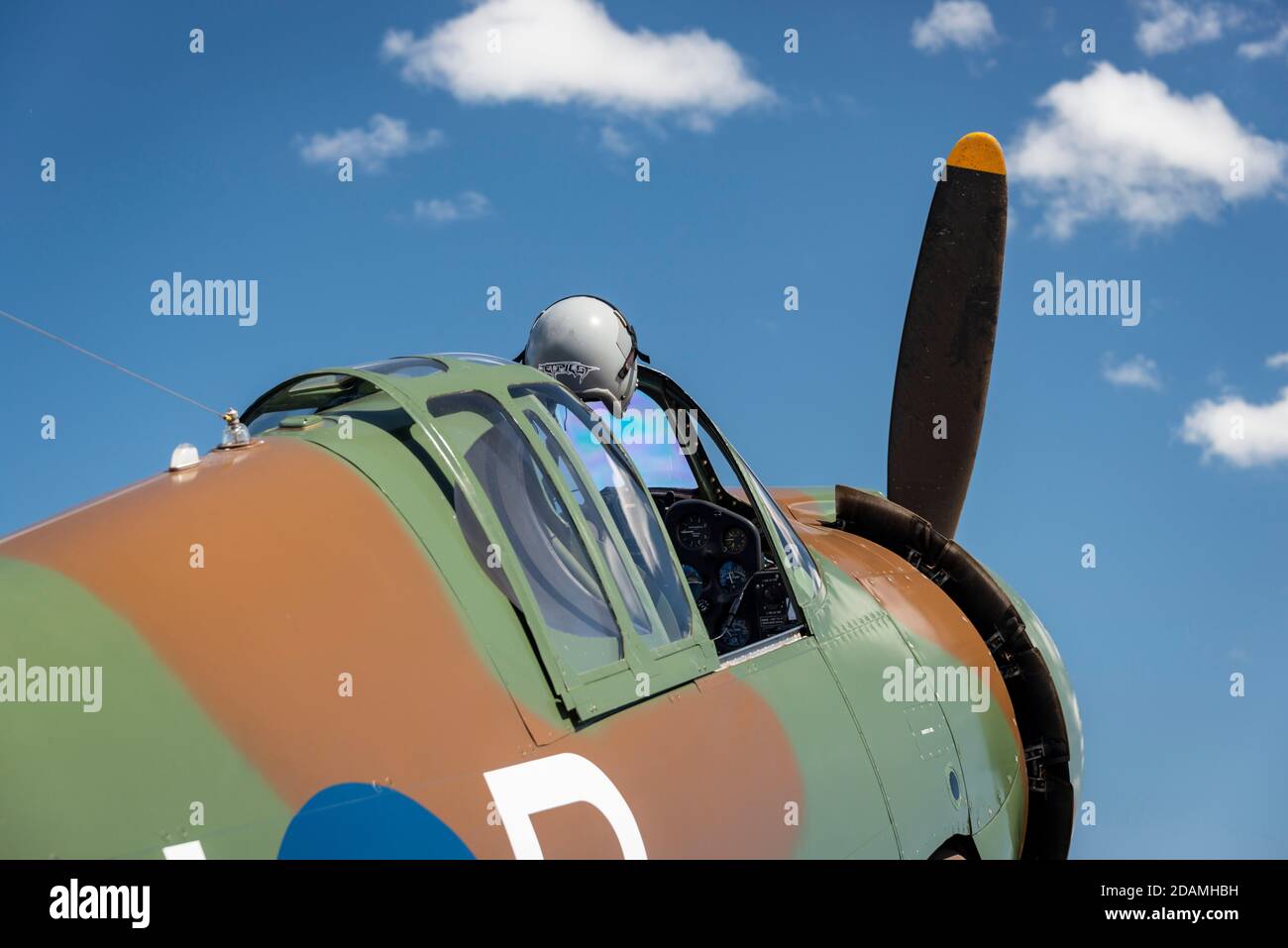 World War 2 aircraft on static display with the cockpit open and a flight helmet. Camoflague paint against a blue sky with a few clouds Stock Photo