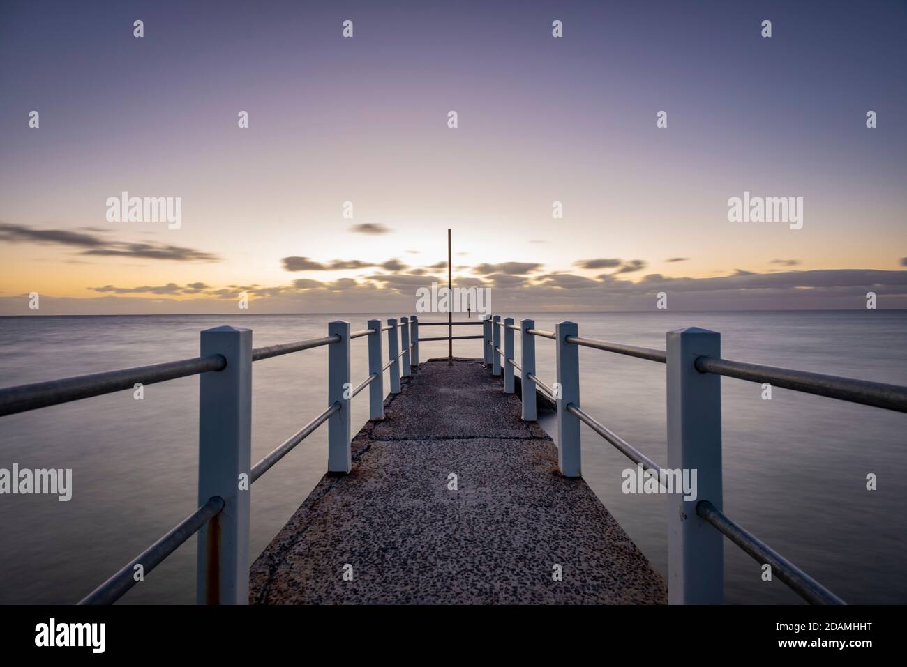 Looking out over a pier against the ocean, a purple dusk horizon sky Stock Photo