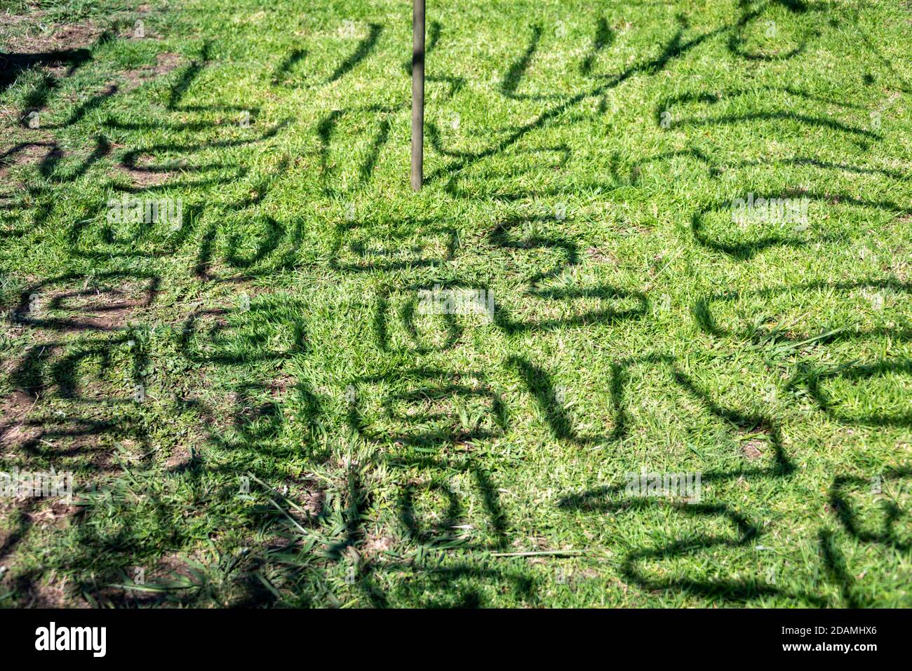 Shadows from military camouflage netting onto grass Stock Photo