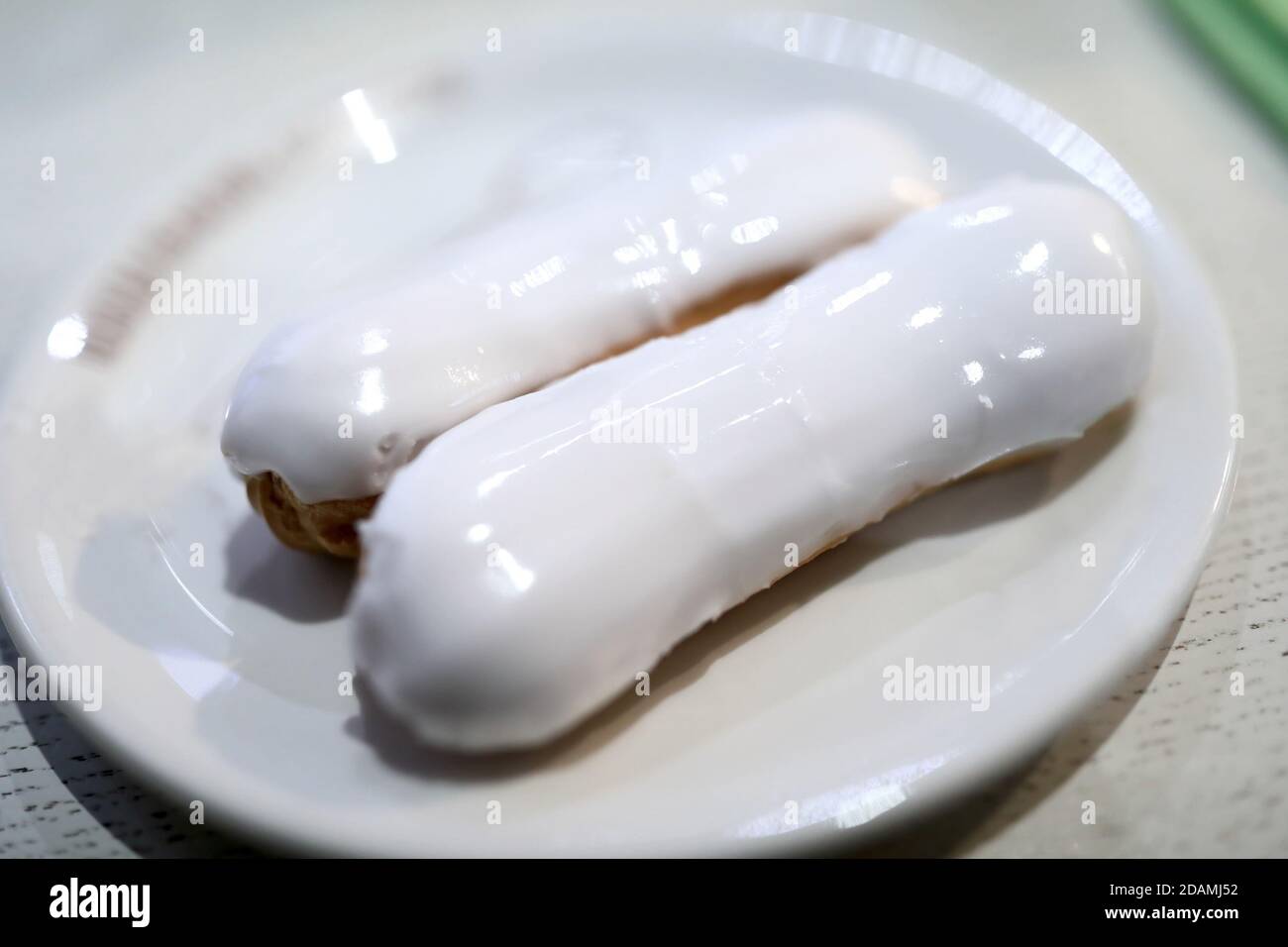 Two vanilla eclairs with icing on plate Stock Photo