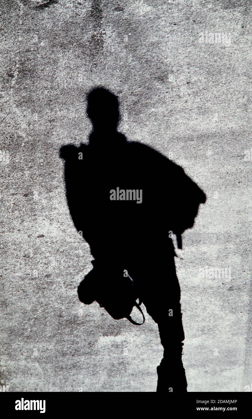 Pedestrian shadows on a blacktop road. A shadow is a dark (real image ...