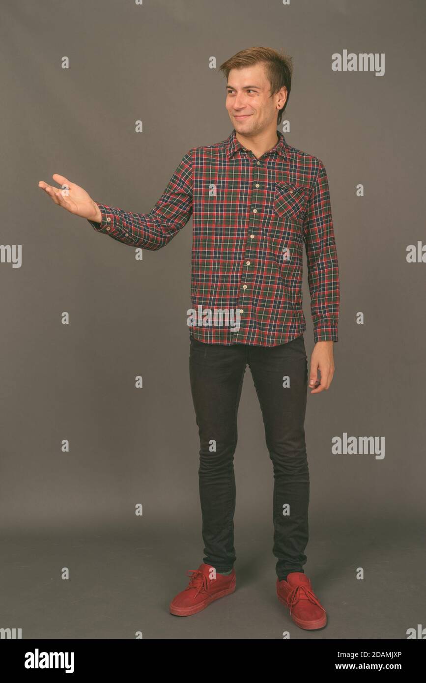 Portrait of young handsome man against gray background Stock Photo - Alamy