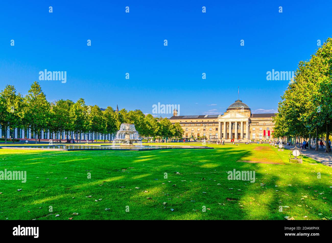 Wiesbaden, Germany, August 24, 2019: Kurhaus or cure house spa and casino building and Bowling Green park with grass lawn, trees alley and pond with fountain in historical city centre, State of Hesse Stock Photo