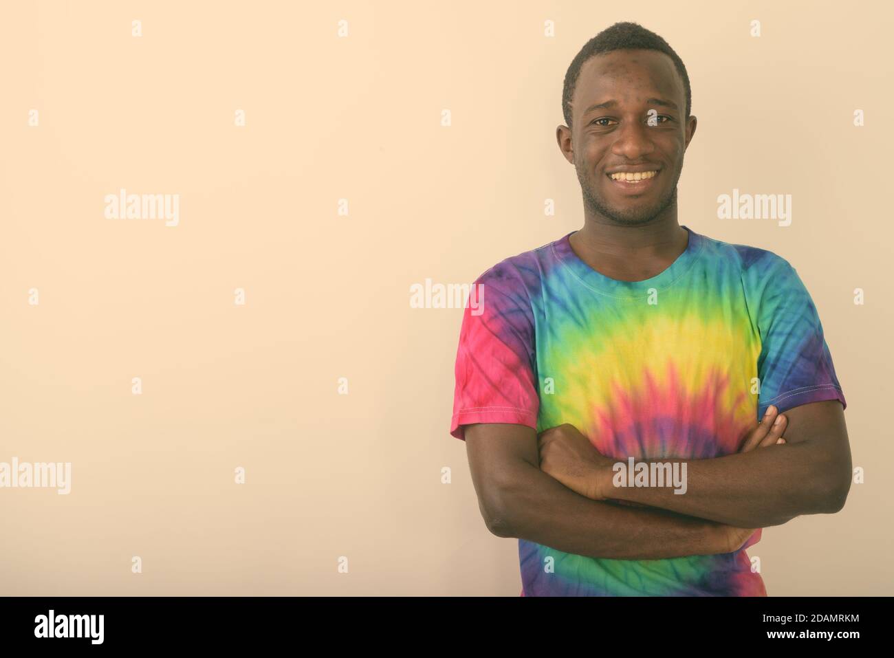 Studio shot of young black African man smiling with arms crossed ...