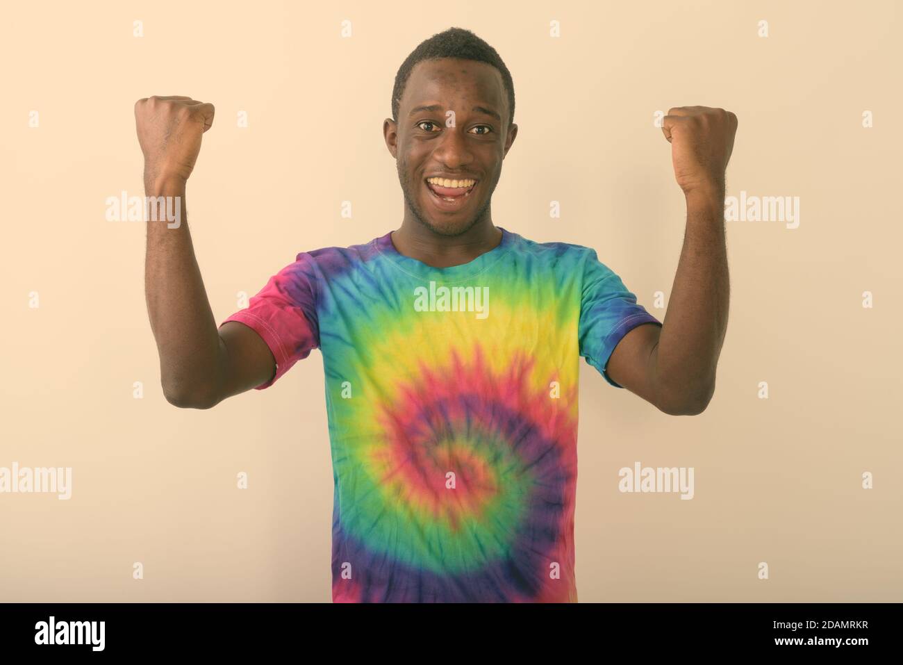 Studio shot of young black African man against smiling with arms raised ...