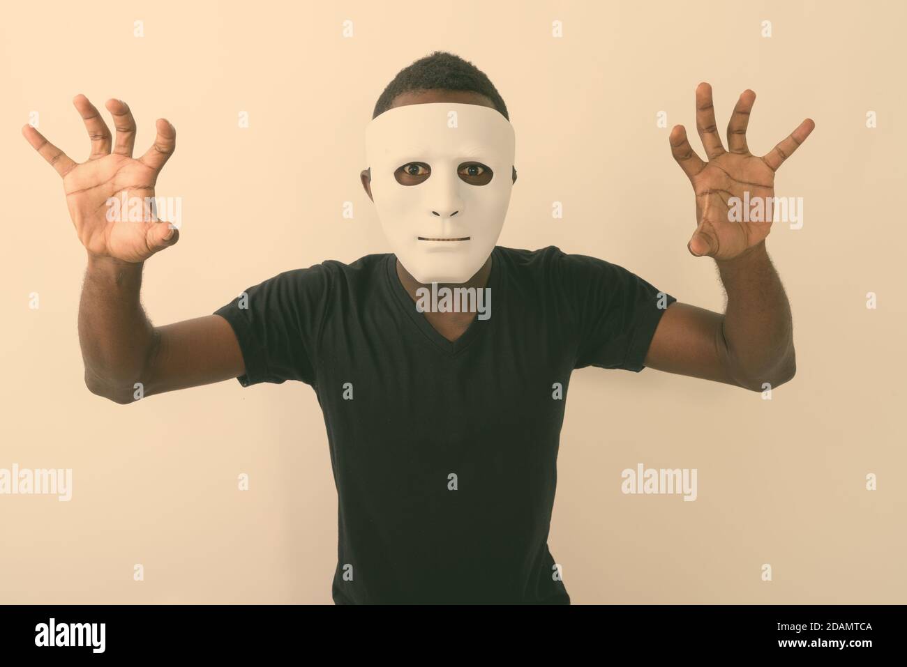 Studio shot of young black African man wearing mask and showing his both hands Stock Photo