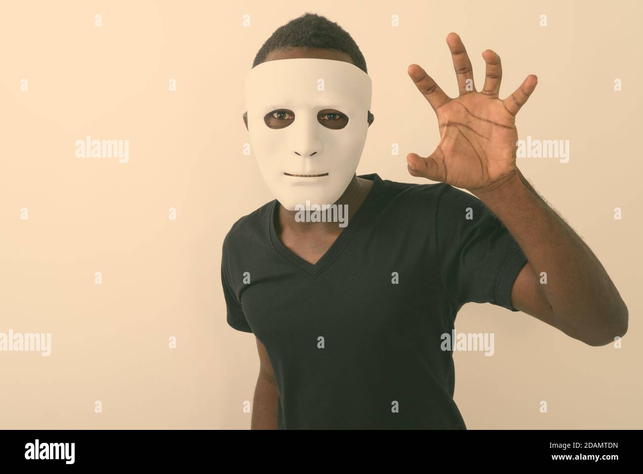 Studio shot of young black African man wearing mask and showing his hand Stock Photo