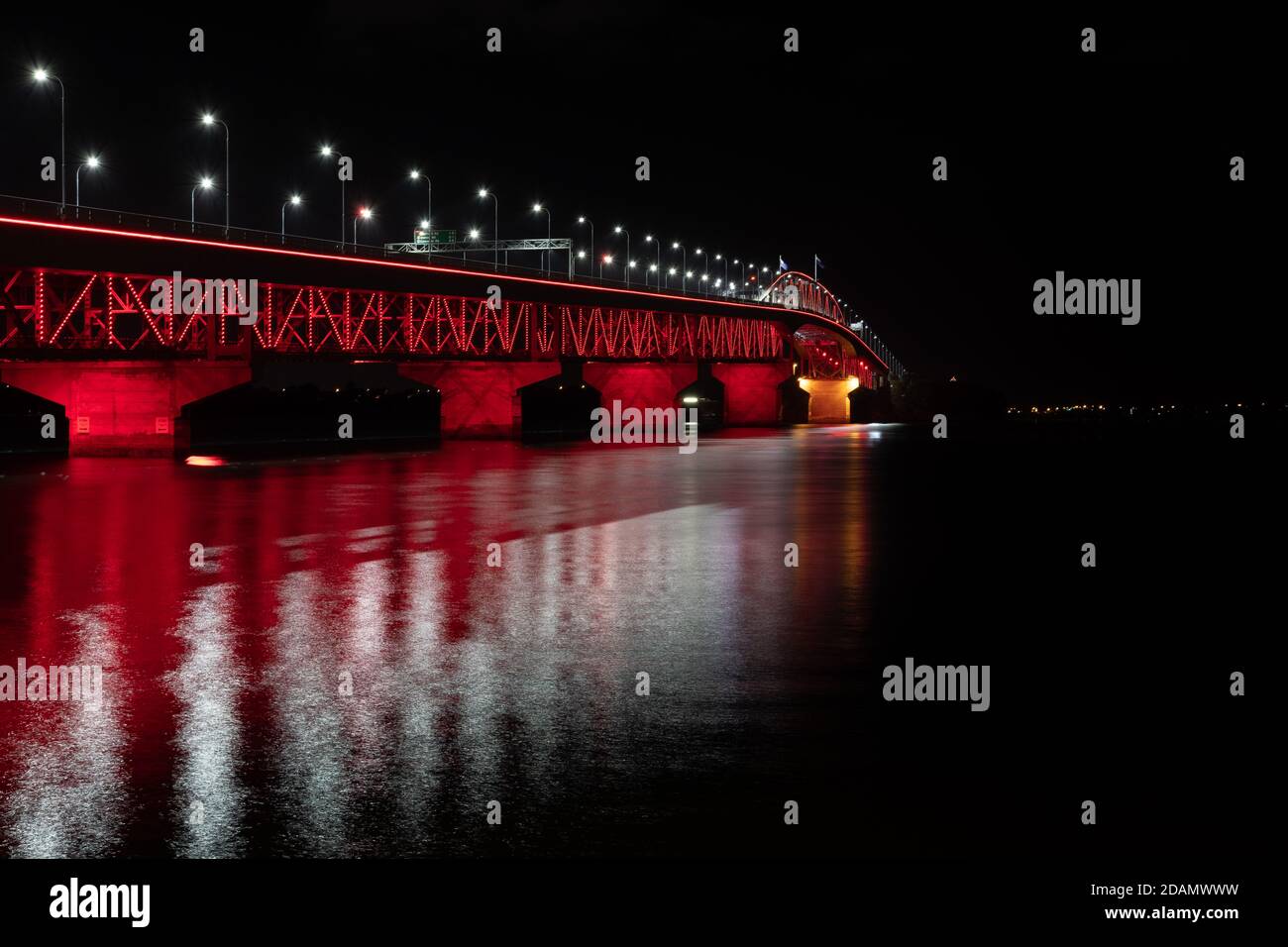 The Auckland Harbour (harbor) Bridge is lit up in red as part of the ANZAC commemoration held on the 25th of April each year. Stock Photo