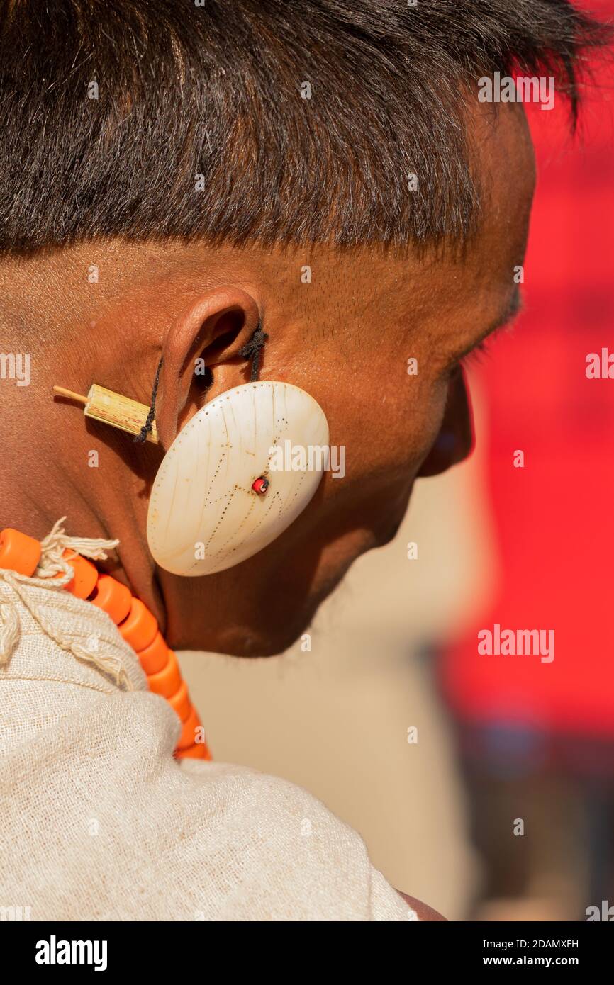 Abstract Portrait of a Naga tribesman dressed in his tribal attire wearing a big white traditional earring at Kisama Nagaland India on 4 December 2016 Stock Photo