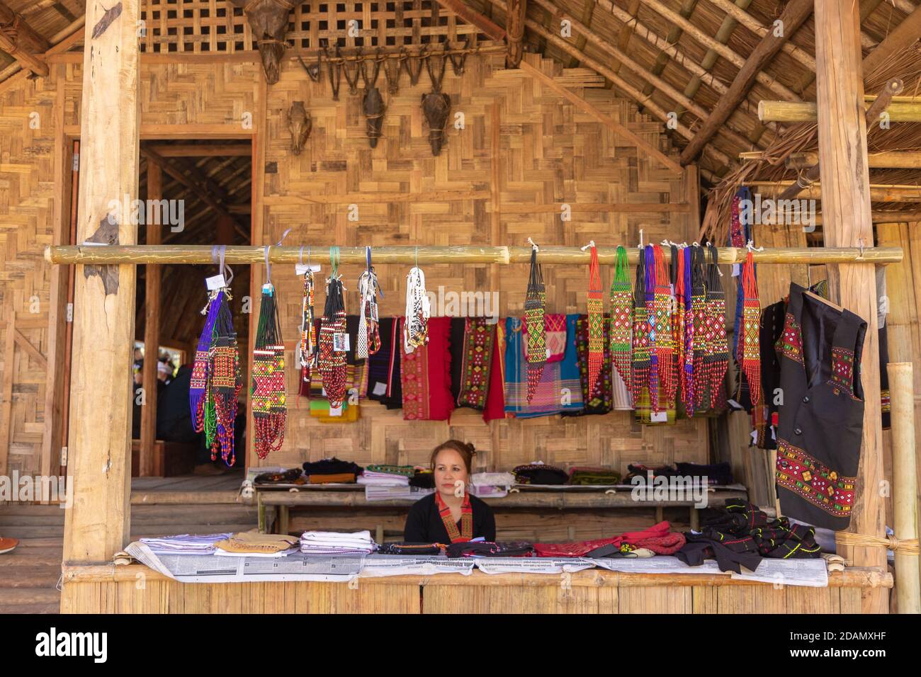 A Nagamese shopkeeper selling local traditional merchandise in a woodwn stall at Hornbill festival at Kisama Nagaland India on 4 December 2016 Stock Photo