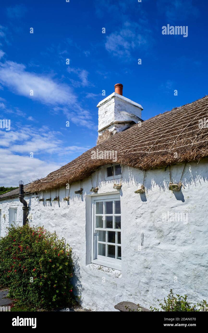 Cottage at Cregneash showing traditional way of tying thatch roofing to projecting stone Stock Photo