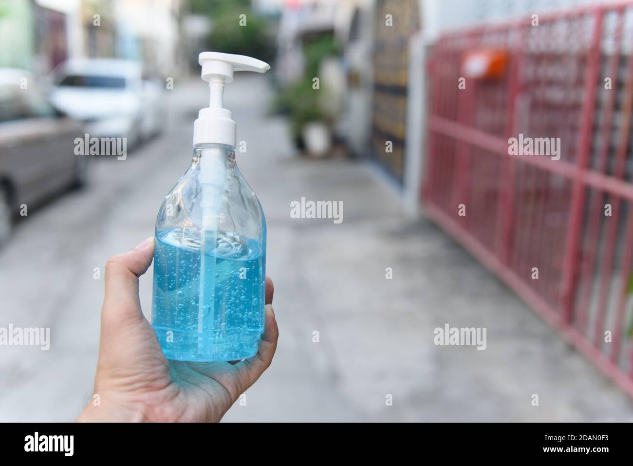 Ethyl Alcohol hand gel in a hand on the street in front of the house, concept for coronavirus, covid19 Stock Photo