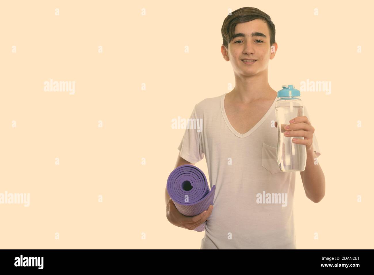 https://c8.alamy.com/comp/2DAN2E1/studio-shot-of-young-happy-persian-teenage-boy-smiling-while-holding-yoga-mat-and-water-bottle-2DAN2E1.jpg