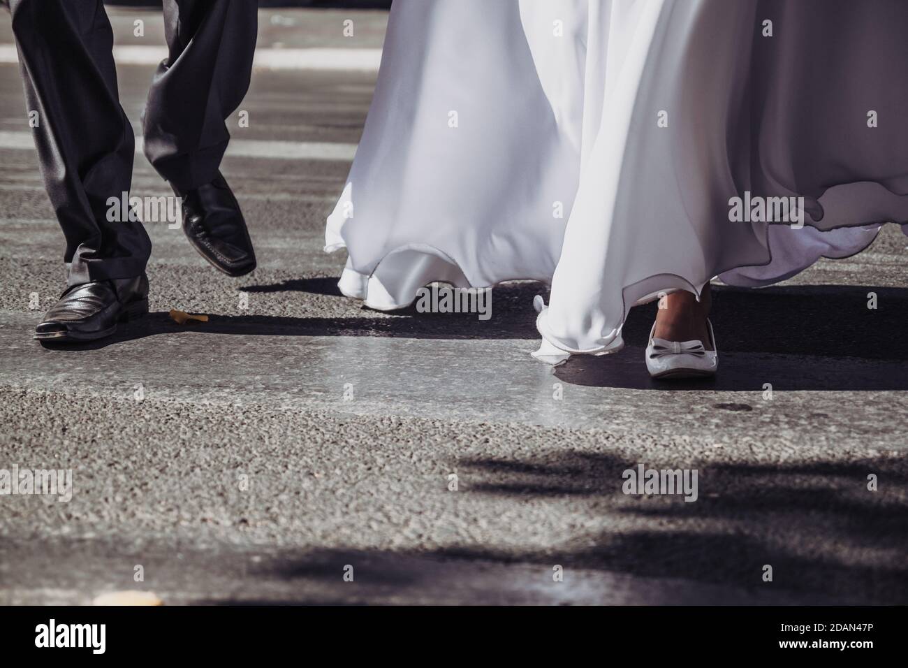 Wedding couple after they just got married. Bride and the groom crossing the street. Elegance, close up, asphalt texture. Stock Photo