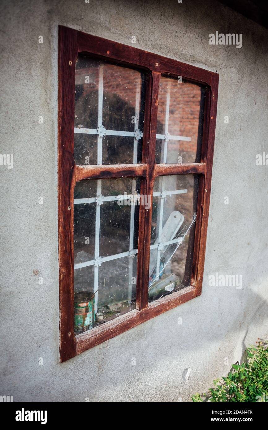 Window of an unfinished house in a small Serbian village. Wooden, dirty glass with reflection. Stock Photo