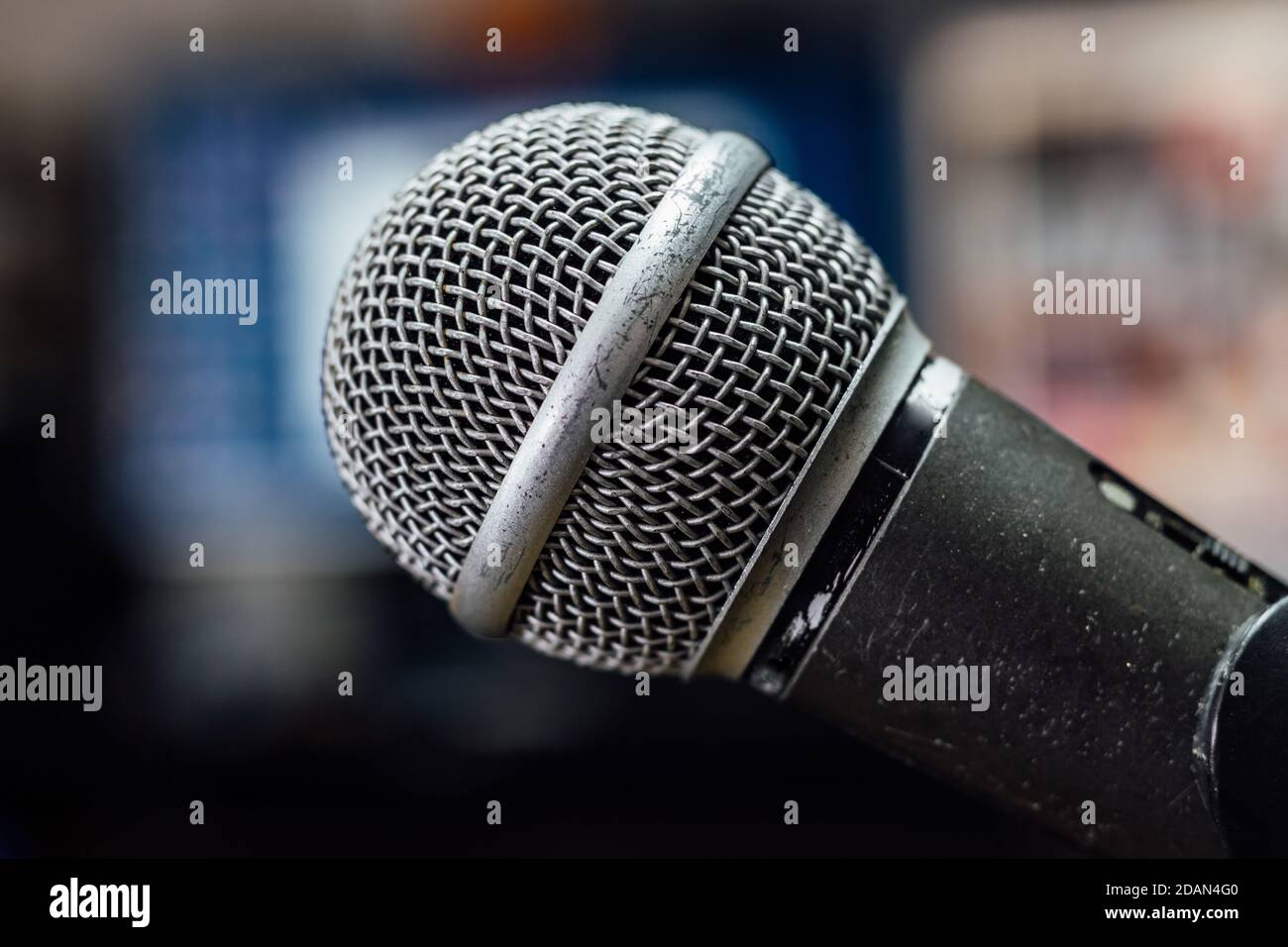 Old, scratched and used microphone on a stand. Blurred background, close up. Stock Photo