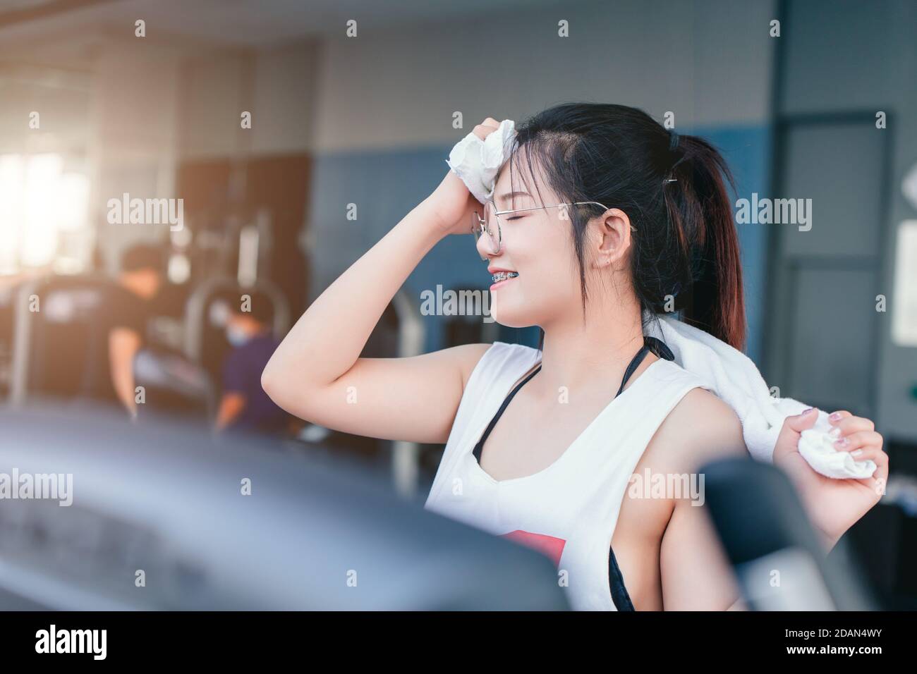 Asian braces girl using towel wiped her sweat after exercise in sport club every morning, she feel happy and smile after workout. Stock Photo