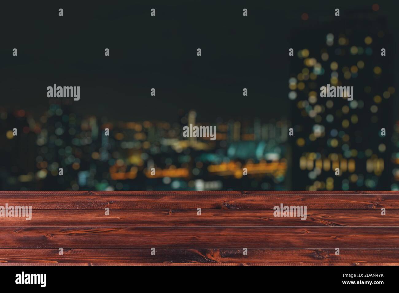 Wooden table top forgound with night city view urban blur background