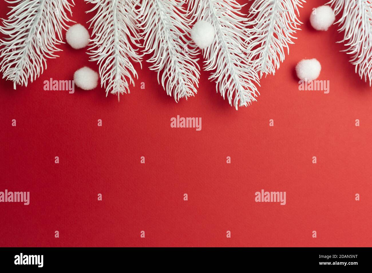 Merry Christmas and Happy New Year greeting card branches frame or banner. White xmas snowflakes and fir tree on red background top view. Winter Stock Photo