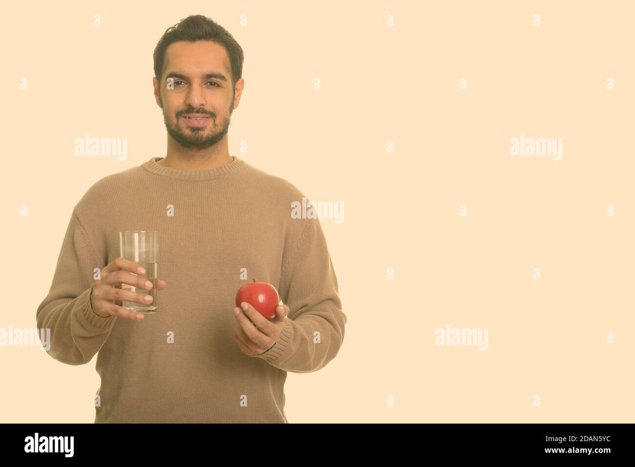 Young happy Indian man holding red apple and glass of water Stock Photo ...