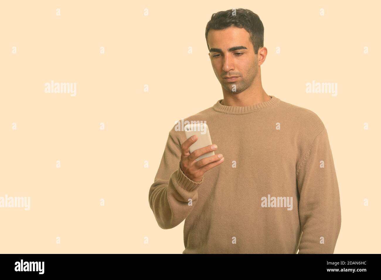 Young handsome Iranian man using mobile phone Stock Photo