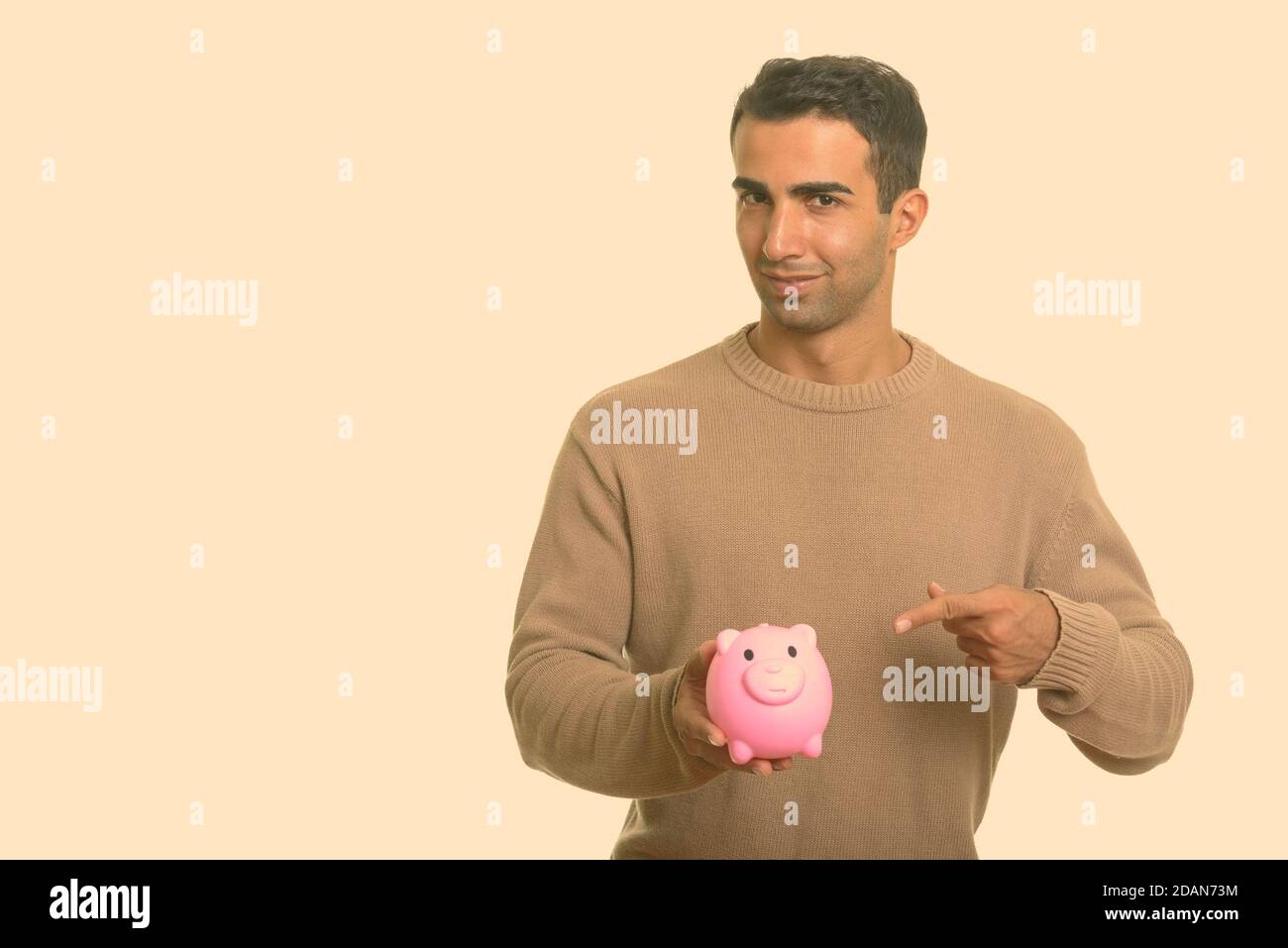 Young handsome Iranian man holding piggy bank and pointing finger Stock ...