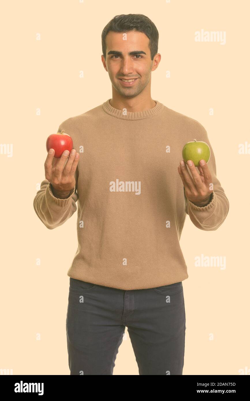 Young happy Iranian man holding red and green apple Stock Photo - Alamy