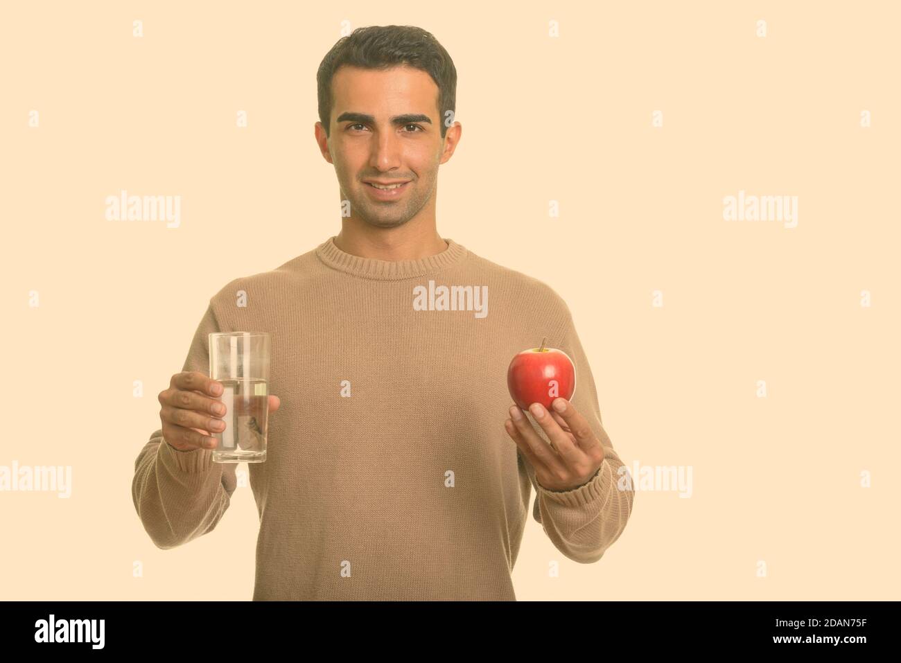 Young happy Iranian man holding red apple and glass of water Stock ...