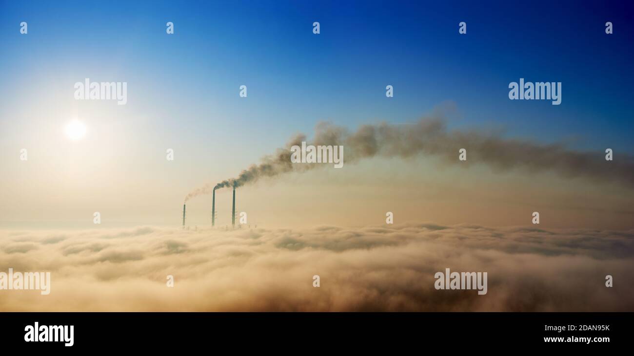 Panoramic view of thermoelectric power plant with dense smoke and colorful sky. Thermal chimneys producing smoke with toxic gases into atmosphere. Concept of energy generation, ecology and pollutions Stock Photo